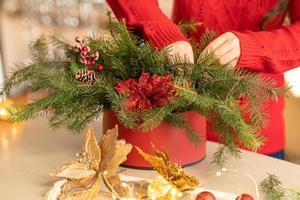 Mädchen sammelt einen Weihnachtsstrauß aus Tannenzweigen, Blumen und Christbaumschmuck foto