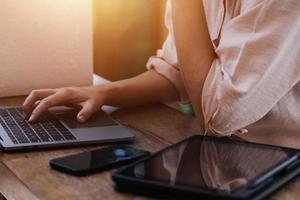 Geschäftsfrau arbeitet mit Laptop-Computer, Tablet und Smartphone im modernen Büro mit virtuellem Symboldiagramm im Modernoffice im Morgenlicht foto