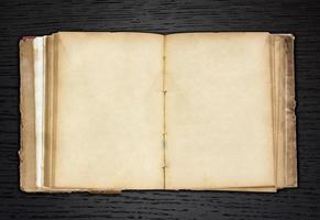 altes Buch offen auf dunklem Holz Hintergrund foto