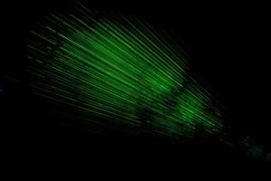 Laser im Dunkeln. grüne Strahlen auf schwarzem Hintergrund. Laserstrahlung im Weltall. foto