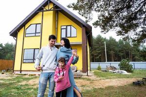 glückliche familie im hof eines unfertigen hauses - kauf eines häuschens, hypothek, kredit, umzug, bau foto