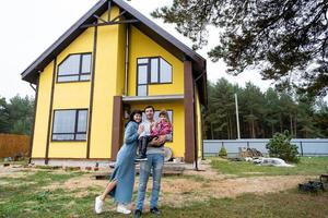 glückliche familie im hof eines unfertigen hauses - kauf eines häuschens, hypothek, kredit, umzug, bau foto