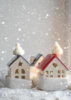 Das gemütliche Haus ist mit Mütze und Schal in ein Schneesturm-Fensterbrettdekor gehüllt. Winter, Schnee - Hausisolierung, Schutz vor Kälte und schlechtem Wetter, Raumheizung. festliche stimmung, weihnachten, neujahr foto