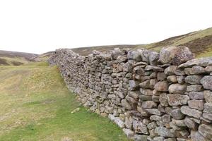 trockene gestapelte Steinmauer mit den Hügeln des Vereinigten Königreichs Yorkshire Dales im Hintergrund foto