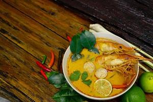 tom yum kung in einer tasse auf einem holzboden, tom yum kung ist auch das nationalgericht thailands. und ist ein Lebensmittel, das auf der ganzen Welt berühmt ist. foto