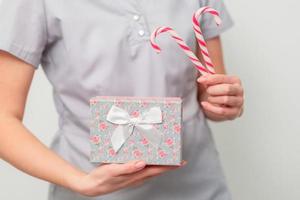 frau in medizinischer uniform mit geschenkbox und weihnachtssüßigkeiten foto