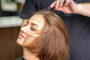 Hand des Friseurs kämmt Haare der jungen Frau foto
