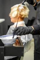 friseur, der haare der jungen frau färbt foto