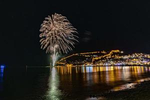 wunderbare reflexion des nächtlichen feuerwerks auf dem meer und stadtmeerblick foto