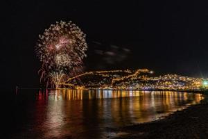 wunderbare reflexion des nächtlichen feuerwerks auf dem meer und stadtmeerblick foto