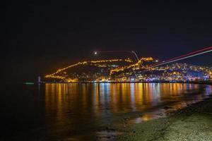 Nachtmeer und Stadtreflexion und Drohnenlichter foto