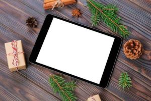 digitales tablet-modell mit rustikalen weihnachtlichen hölzernen hintergrunddekorationen für app-präsentation. draufsicht mit kopierraum foto