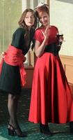 Ganzkörperporträt eleganter junger Frauen mit Weingläsern auf der Feierparty. schwarzes und rotes Outfit. foto