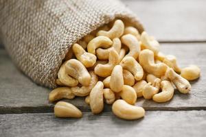 Cashew-Nüsse in Sackleinen auf hölzernem grauem Hintergrund. gesundes Essen foto