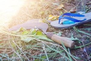 ein Bauernwerkzeug namens Cengkrong-Sichel und Flip-Flops foto