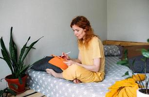 Frau, die von zu Hause aus auf dem Bett arbeitet und ein Grafiktablett für Design und Zeichnung verwendet foto