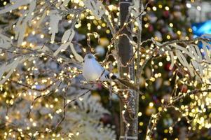 Weihnachtsschmuck für das Einkaufszentrum. hohe Bäume, die mit leuchtend gelben Girlanden geschmückt sind. Vögel aus künstlichen Materialien sitzen auf den Zweigen. Handarbeit foto