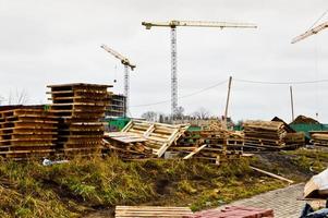 Eine große moderne Baustelle im Bau von Gebäuden und Häusern mit Geräten und vielen großen hohen Türmen und stationären industriellen leistungsstarken Kränen und Baumaterialien foto