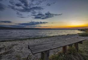 einsame bank am meer bei sonnenuntergang foto