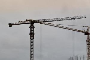 Großer leistungsstarker Industriekran für Bauladungen auf einer Baustelle mit neuen Gebäuden und Häusern gegen den Himmel foto