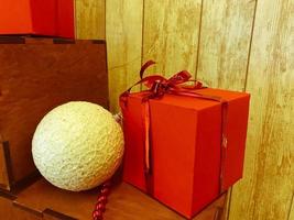 eine kleine niedliche weiße weihnachtsbaumdekoration, eine kugel und festliche neujahrsdekoration und eine rote geschenkbox foto