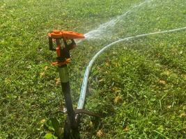 Automatischer Sprinkler für grünes Gras, Wassersprüher zum Gießen von Rasenpflanzen foto