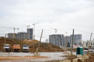 Bau von großen modernen monolithischen Fachwerkhäusern, Gebäuden mit Industriebaumaschinen und großen hohen Kränen. Bau des Gebäudes im neuen Mikrobezirk der Stadt foto