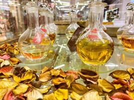 Parfums in durchsichtigen Flakons. Duftmischung, Parfümessenz, Labor mit Flüssigkeiten in Fläschchen auf Blütenblättern. dekorierte Vitrine mit Parfüm foto