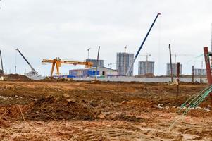 Bau eines neuen Mikrobezirks mit hohen Häusern, Neubauten mit ausgebauter Infrastruktur mit Hilfe großer Industriekräne und professioneller Baumaschinen in einer Großstadt foto