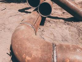 Metallrohr liegt auf dem Boden. Verlegung der Kommunikation für Wohngebäude unter der Erde. Wasser leiten. rostiges, altes, schmutziges Metallrohr foto