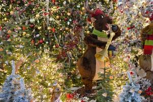 Weihnachtsdekoration für ein Einkaufszentrum. in der mitte spielt ein hirsch saxophon. Hirschmusiker macht Kinder glücklich. Fichtenzweige sind mit Perlen und bunten Kugeln verziert foto