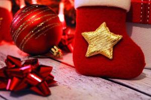 weihnachtsroter und goldener hintergrund mit kugeln, bögen, weihnachtssocke und geschenken foto