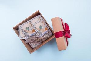 offene geschenkbox gefüllt mit geld auf hellblauem hintergrund. foto