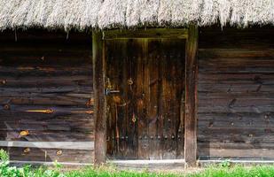 Alte verwitterte Tür in der Holzwand einer alten Hütte foto