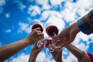 Menschen, die auf der Sommerterrasse des Cafés oder Restaurants mit Wein anstoßen foto