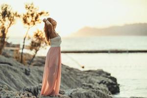 Frau, die den Sonnenuntergang am Strand genießt foto