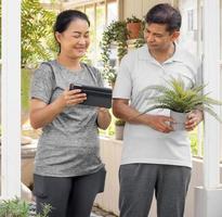 zwei Menschen mittleren Alters, die als Hobby pflanzen, Porträt. lächelnd paar person glücklich freizeit gartenarbeit im freien. reifer ehemann und ehefrau gartenbau haben einen sorglosen gesunden lebensstil, der pflanzen anbaut. foto