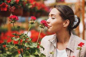 Floristin riecht Blumen, während sie sich in einem Gartencenter um sie kümmert foto