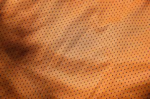 Sportbekleidung Stoff Textur Hintergrund. Draufsicht auf die Textiloberfläche aus orangefarbenem Polyester-Nylon-Tuch. farbiges Basketballshirt mit freiem Platz für Text foto