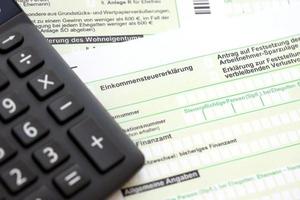 die deutsche jährliche einkommensteuererklärung und der rechner liegen auf dem buchhaltertisch aus nächster nähe. das konzept der steuerzahlzeit in deutschland foto
