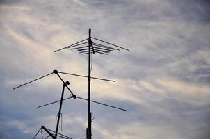 Eine alte und rostige Fernsehantenne vor einem bewölkten blauen Himmel foto