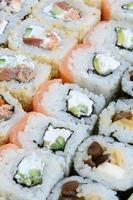 Nahaufnahme vieler Sushi-Rollen mit verschiedenen Füllungen. Makroaufnahme gekochter klassischer japanischer Speisen. Hintergrundbild