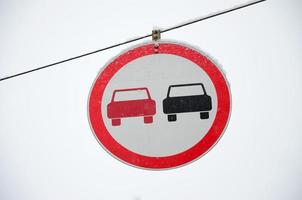 Straßenschild. Überholen ist verboten. das Schild verbietet das Überholen aller Fahrzeuge auf dem Straßenabschnitt. Ein rot-schwarzes Auto ist in einem umrahmten roten Kreis dargestellt foto