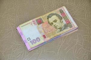 Eine Nahaufnahme eines Satzes ukrainischer Geldscheine mit einem Nennwert von 100 Griwna, die auf einer braunen Lederoberfläche liegen. hintergrundbild auf geschäft in der ukraine foto