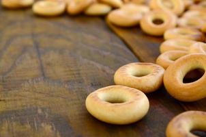 viele frische gelbe bagels liegen auf der oberfläche des alten dunklen holzes. eine beliebte Art von Mehlprodukten. eine der traditionellen russischen Leckereien für Tee foto