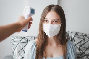 Temperatur der Frau in Maske nehmen foto