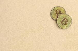 Zwei goldene Bitcoins liegen auf einer Decke aus weichem und flauschigem hellorangefarbenem Fleecestoff. physische Visualisierung der virtuellen Kryptowährung foto