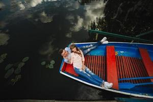 Ein Paar, das auf einem blauen Boot auf einem See reitet. Romantik. emotionales Paar. lustig und verliebt foto