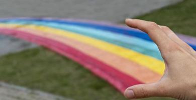 menschliche hand, die einen regenbogenpfad auf der stadtstraße freigibt, kopierraum, liebe, freiheit und freundschaft, abstrakt foto