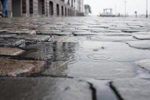 Pfütze mit Regentropfen auf einer asphaltierten Straße im Regen foto